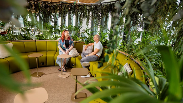 Two employees are talking casually on a curved sofa inside Calon, Legal & General's Welsh HQ
